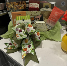Load image into Gallery viewer, A delightful blend of gourmet flavors, this gift basket brings together the perfect harmony of savory snacks and sweet indulgences. Thoughtfully curated and beautifully arranged in a charming pear-shaped wicker tray, it’s wrapped with a garden-themed bow that celebrates fresh, wholesome goodness.