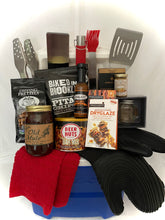 Load image into Gallery viewer, Inside, you’ll find:
A 5-piece Expert Grill toolset
Iron Chef silicone mitts a hand towel
Gourmet dry rubs, glazes, BBQ sauce mustard Snacks like dipping pretzels, baked chips, cheese, and beer nuts
Ball jar salt & pepper shakers for the perfect seasoning.