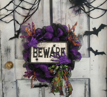 Load image into Gallery viewer, Step into the haunted realm of spookiness with our &quot;BEWARE&quot; Halloween multi-colored mesh wreath! This wickedly delightful wreath is the perfect way to &quot;scream beware&quot; and add a haunting touch to any door or wall! It&#39;s approximately 38&quot; in diameter and 6&quot; deep, making it a grand and eerie statement piece.
Embellished with a plaque, creepy hands, and enchanting picks, this wreath brings the Halloween spirit to life! And let&#39;s not forget the show-stopping handmade bow, bursting with all the chilling colors of