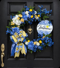 Load image into Gallery viewer, A layered designer bow showcases luxurious blue, yellow and white patterned ribbons paired with sunny lemon-print accents, creating a rich and eye-catching statement piece.
Finished with a charming “Welcome” sign, this wreath offers a warm and inviting greeting for guests while bringing beauty and elegance to any front door, entryway, or covered porch. Perfect for spring and summer décor, this custom silk floral wreath is a timeless piece designed to brighten your home season after season.
