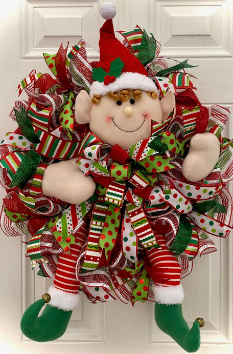 Step into the enchanting world of the holidays with this breathtaking handmade wreath! Crafted with meticulous attention to detail, this whimsical creation features the delightful charm of an elf, woven seamlessly into a stunning 26-inch diameter wreath.  Adorned with an array of vibrant holiday and festive ribbons, this masterpiece is a true testament to the spirit of the season. 