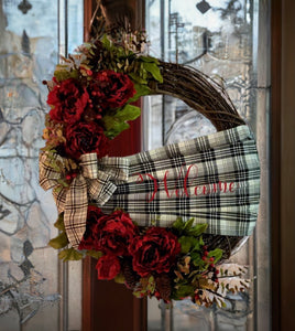 This exquisite wreath is embellished with a captivating handmade buffalo print Sache, graciously welcoming all who approach. Adorned with opulent burgundy silk flowers, lush greens, vibrant berries, and charming pine cones, the wreath showcases nature's finest hues in a harmonious dance of color and texture. The crowning glory is a meticulously crafted handmade bow, adding a touch of artistry and personal flair to the overall masterpiece.