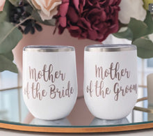 Load image into Gallery viewer, Celebrate with Elegance – Custom &quot;Mother of the Bride&quot; &amp; &quot;Mother of the Groom&quot; Stemless Wine Goblets

Our beautifully crafted stemless wine goblets blend rose gold vinyl with a pristine white background, offering a touch of sophistication. These 14oz stainless steel tumblers keep beverages warm or chilled and come with a secure lid.

Customize yours with names, monograms, quotes, or colors to create a truly personal keepsake. Each tumbler is handmade with care, ensuring top quality.