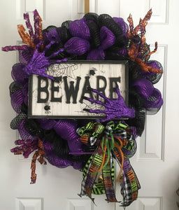 Due to product availability, we no longer can make this exact wreath. We can make customized wreaths by color, size, picks, and signs.  "BEWARE"... This Halloween multi-colored mesh wreath is a perfect wreath that SCREAMS "BEWARE" ...and is perfect for any door or wall as a decor. It measures approximately 30" in diameter x 6"deep. It is embellished with a wooden plaque, resin hands, embellished curl picks, and a handmade bow full of Halloween colors. 