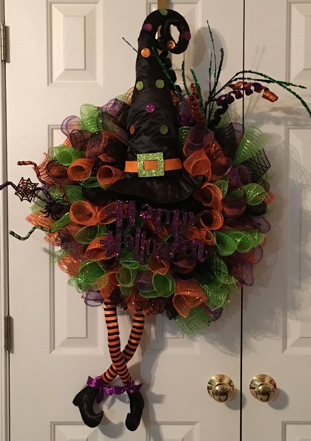 This Happy Halloween Wreath is a colorful mesh wreath perfect for any room, door, or wall. It's the kind of wreath that welcomes all your ghoulish friends with vibrant colors. It's bright and decorated with a witch's hat, witches' legs, and a variety of embellishments and colorful mesh. It measures approximately 40