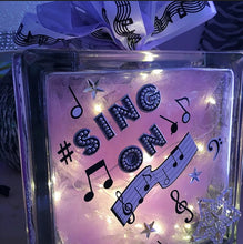 Load image into Gallery viewer, Music Block in Purple is perfect for any kid, baby, or playroom. This block is stenciled, filled with lights, purple tulle, with music notes and music ribbon. These have battery-operated lights or we can use plugged lights. We can customize these blocks by color choice and gender. These are perfect for a child&#39;s night light. Please allow 1-2 weeks for delivery. These can be shipped nationwide. 
