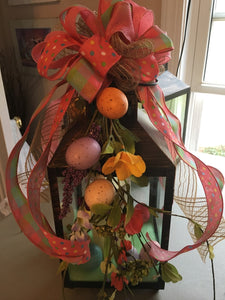 Spring Lantern is a wonderful centerpiece for your dining table, side table, or countertop. This lantern has a large led battery-operated candle decorated with Easter eggs, silks, and a beautiful handmade bow. It measures appx. 15"tall x 6" x 6" perfect for any room. We can customize lanterns for any occasion or for any room. Please allow 1-2 weeks for delivery.