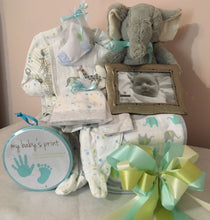 Load image into Gallery viewer, A New Baby in Town....is one of our &quot;Best Sellers!&quot; Our neutral color baby gift allows parents to create memorable keepsakes and have necessities for their new baby. Nothing says welcome baby like these beautifully hand-selected neutral color gifts appropriate for either gender. This gift will come with a mixture of a neutral color comfy outfit, socks, bibs, toy, picture frame, baby keepsake and so much more for any new parent to pamper their new baby with. Colors may vary.