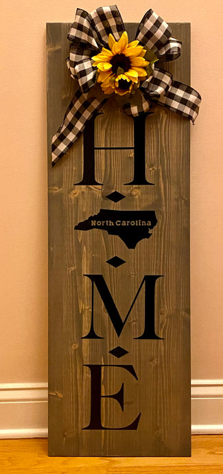 This board is 4’ tall x 1’ wide approximately and stained in a gray stain, with vinyl lettering and finished with polyacrylic. It has a beautiful handmade bow with sunflower and nothing says Welcome home like it! Perfect for your North Carolina entryway! We do not ship these boards. We can locally deliver or can be picked up. Please allow 1-2 weeks for delivery. Greet your guests with this beautifully handmade welcome!