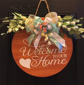 Welcome to Our Home" is a "BEST SELLER!" This beautiful handmade door or wall decor is made of real pine wood. This piece has been sanded and stained to bring out the true beauty of the wood. It has a white permanent vinyl quote, and silk flowers with a matching beautiful handmade bow. The decorative three-strand hanging rope has guides to prevent sliding and cork protectors are on the back of this decor to protect your wall or door. 