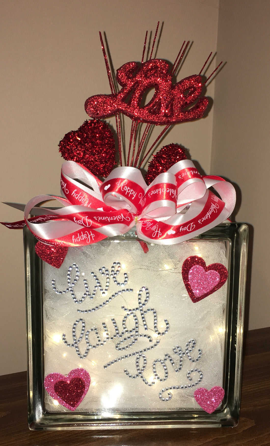 This Valentine's Day Block lights up with battery-operated lights. We can customize a saying and add names with vinyl-only not rhinestones. We can design this block the way you want with different colors. This is a double-sided block that can be placed anywhere or in any room to decorate for Valentine's Day! Decorative picks and ribbons may vary.